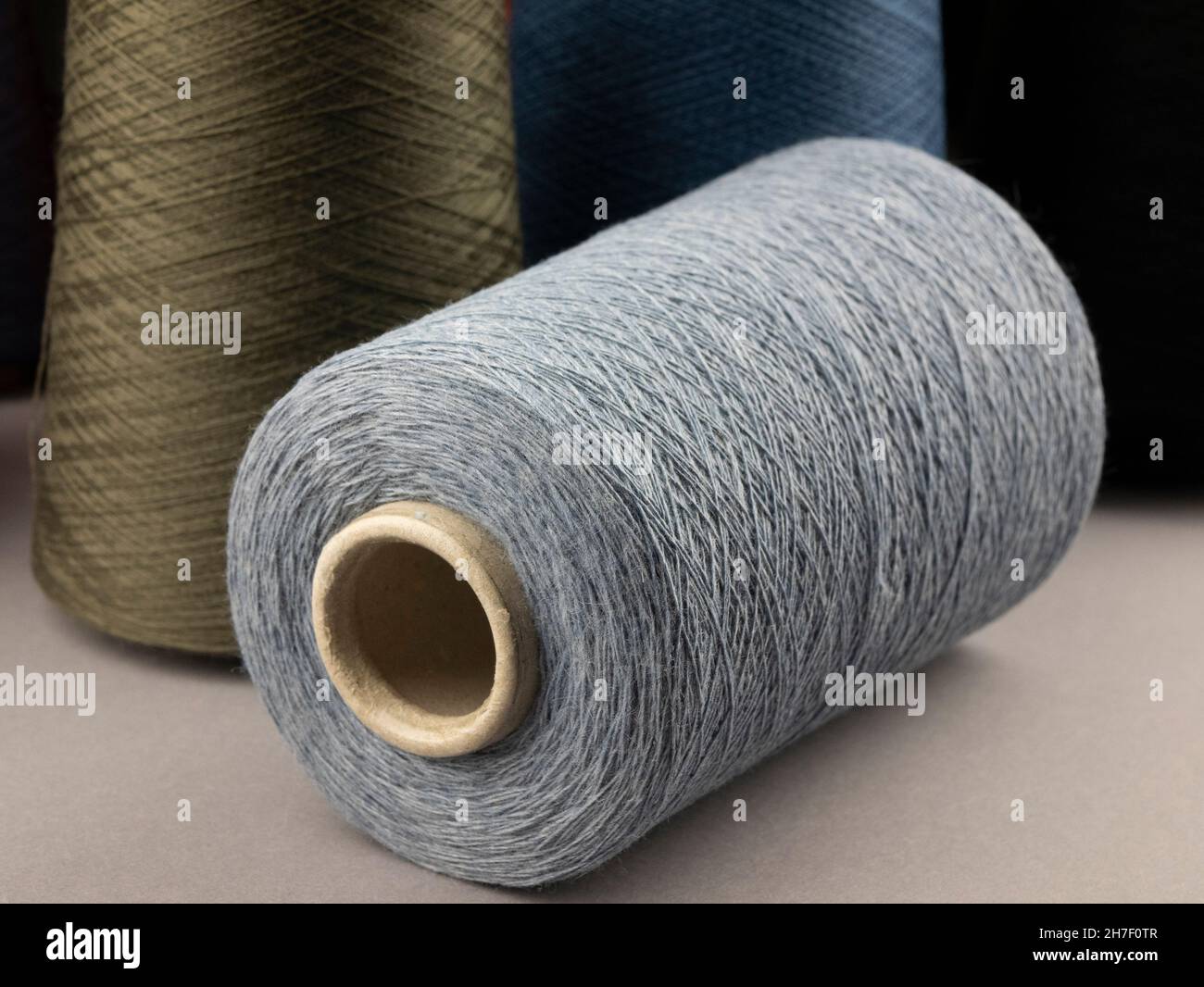 Cones of neutral tones threads. Bobbins of cotton, woolen or synthetic yarn for textile manufacturing or handmade products, close up Stock Photo