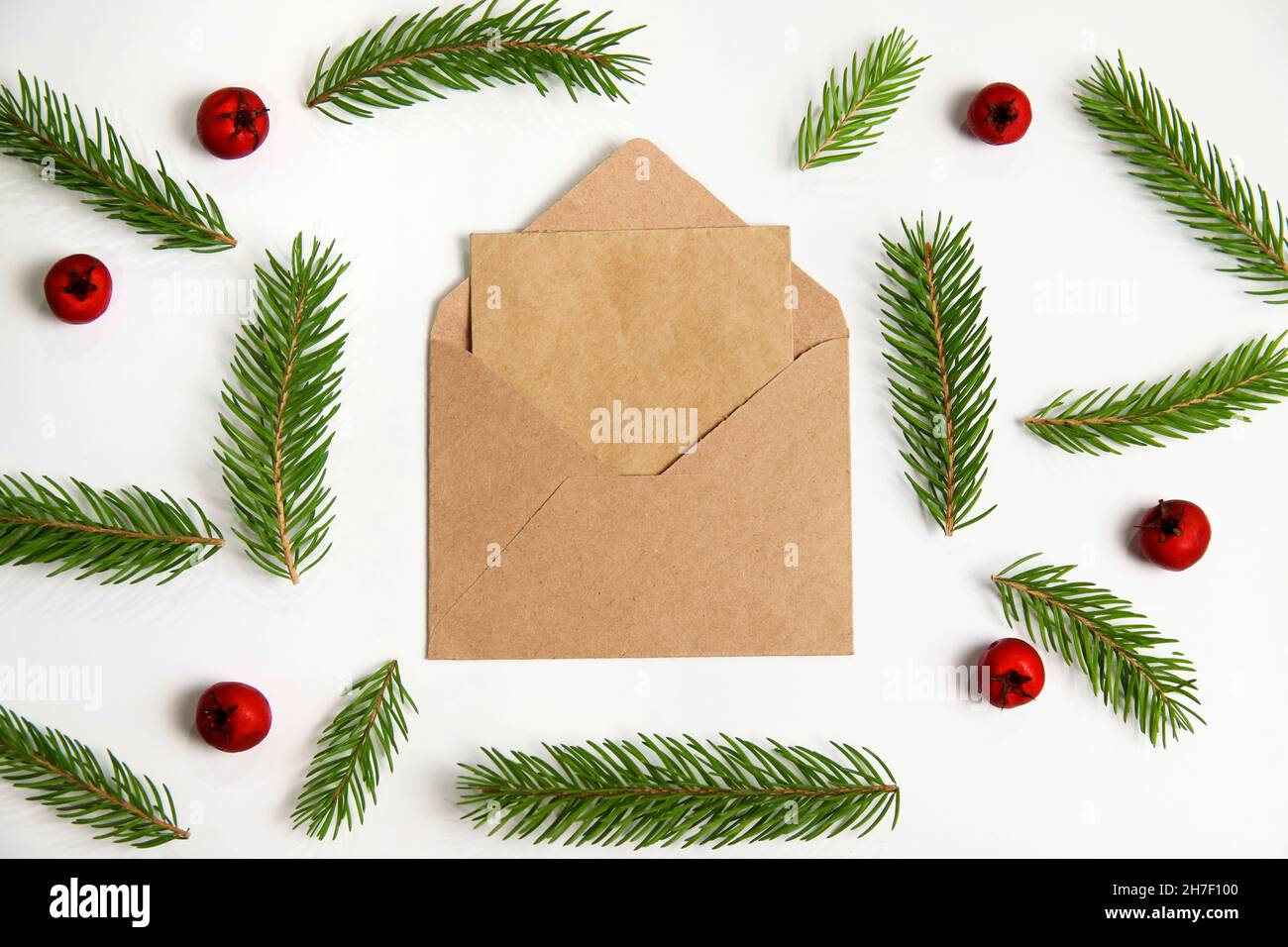 Closeup eco craft envelope, letter to Santa. Frame of fir branch or spruce branch and red berries isolated on white background. Fir tree branches Stock Photo