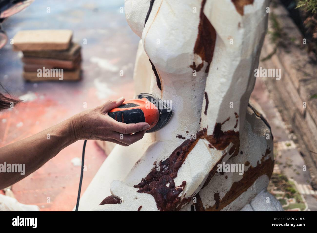 Polystyrene Hand Hand of a woman using an electric polisher on a polystyrene figure ...
