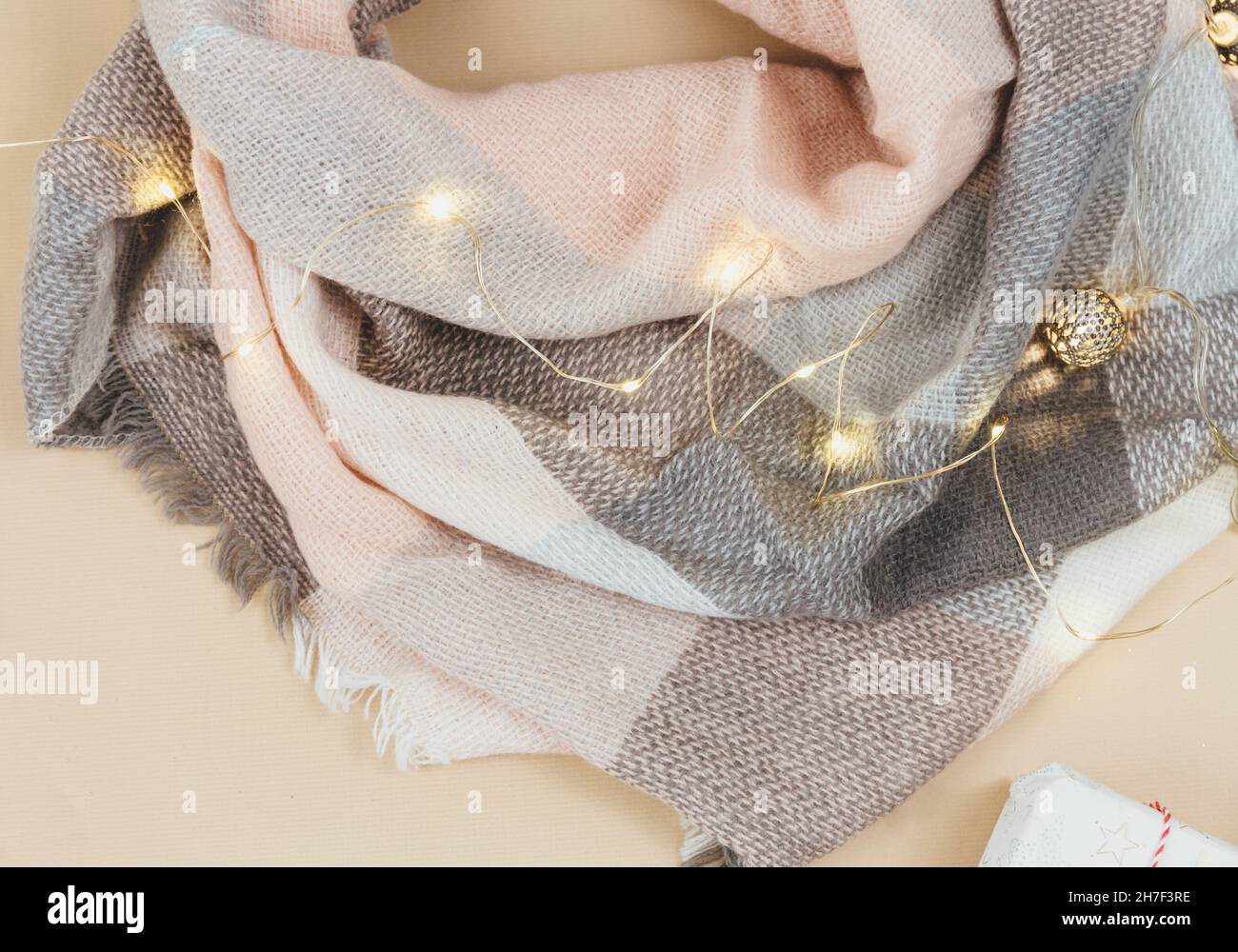 Women fashion winter clothes and accessories. Female look with knitted white and pink scarf, garlands on beige pastel background. Stock Photo
