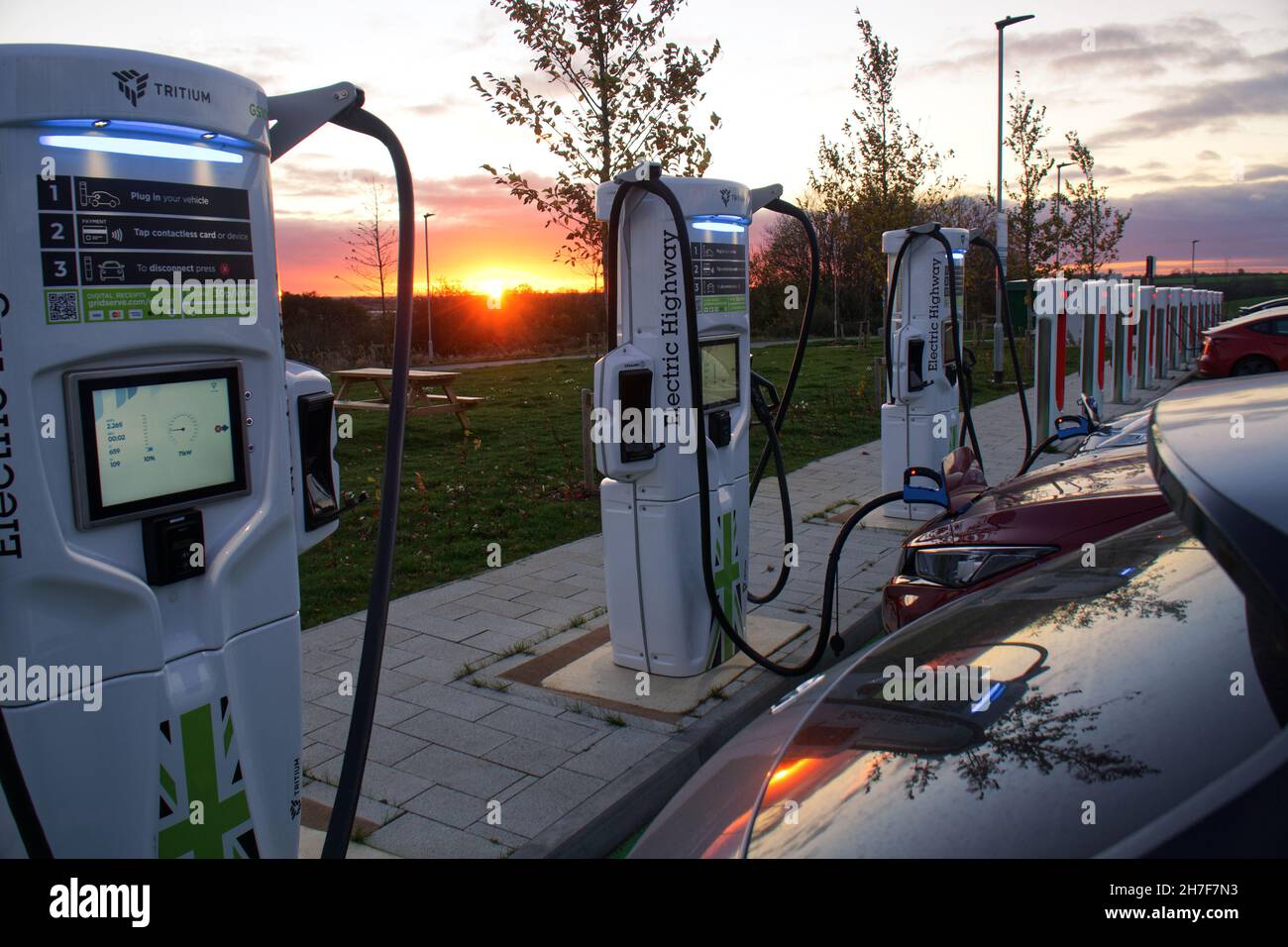 Electric vehicles charging at sunset at the Gridserve Electric Highway fast chargers in Rugby, England Stock Photo