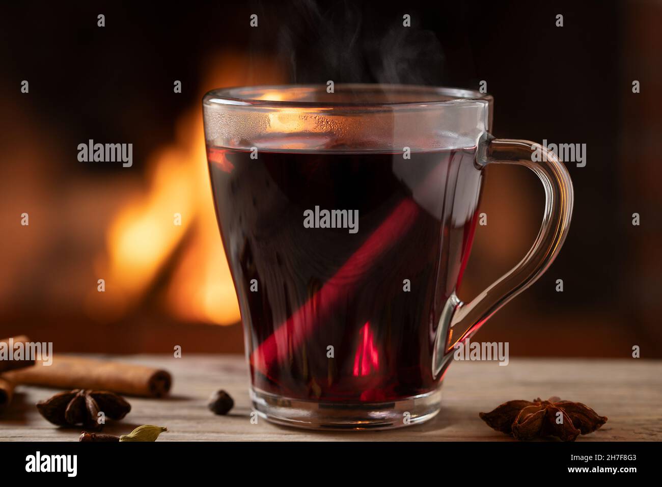Glass mug with hot mulled wine by the burning fireplace Stock Photo