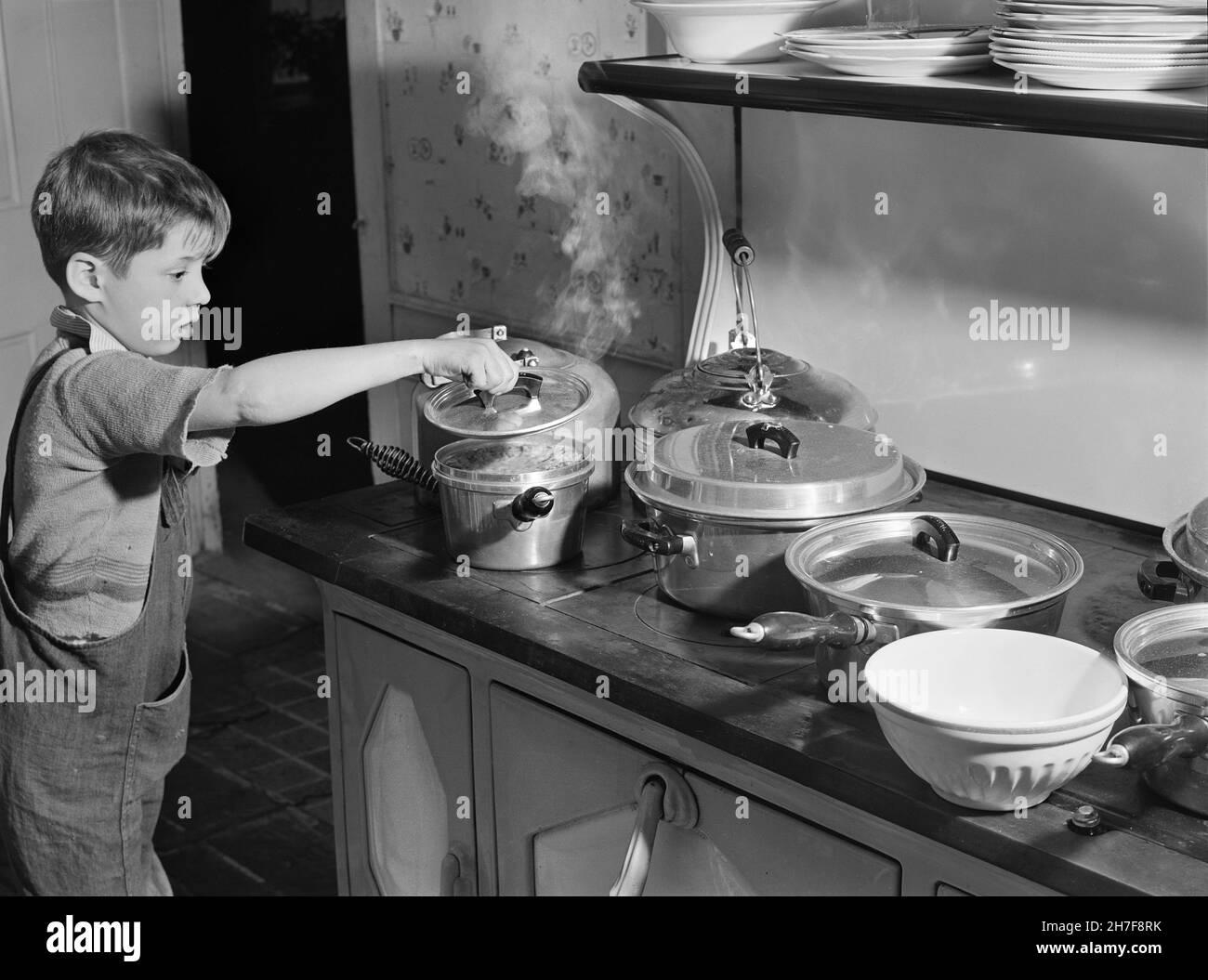 Young Boy checking Pots of Food on Stove for Thanksgiving Dinner, Ledyard, Connecticut, USA, Jack Delano, U.S. Farm Security Administration, U.S. Office of War Information Photograph Collection, November 1940 Stock Photo