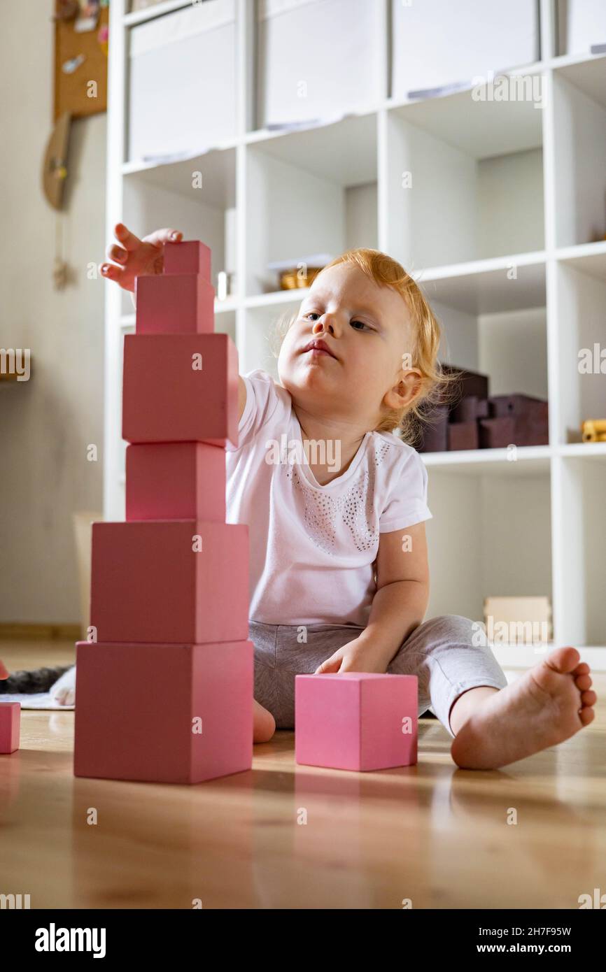 Cheerful toddler arrangement pink cubes assembling tower educational
