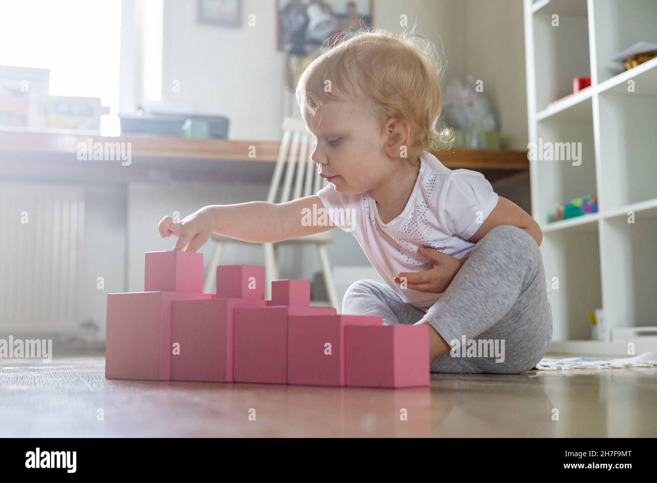 Cheerful toddler arrangement pink cubes assembling tower educational