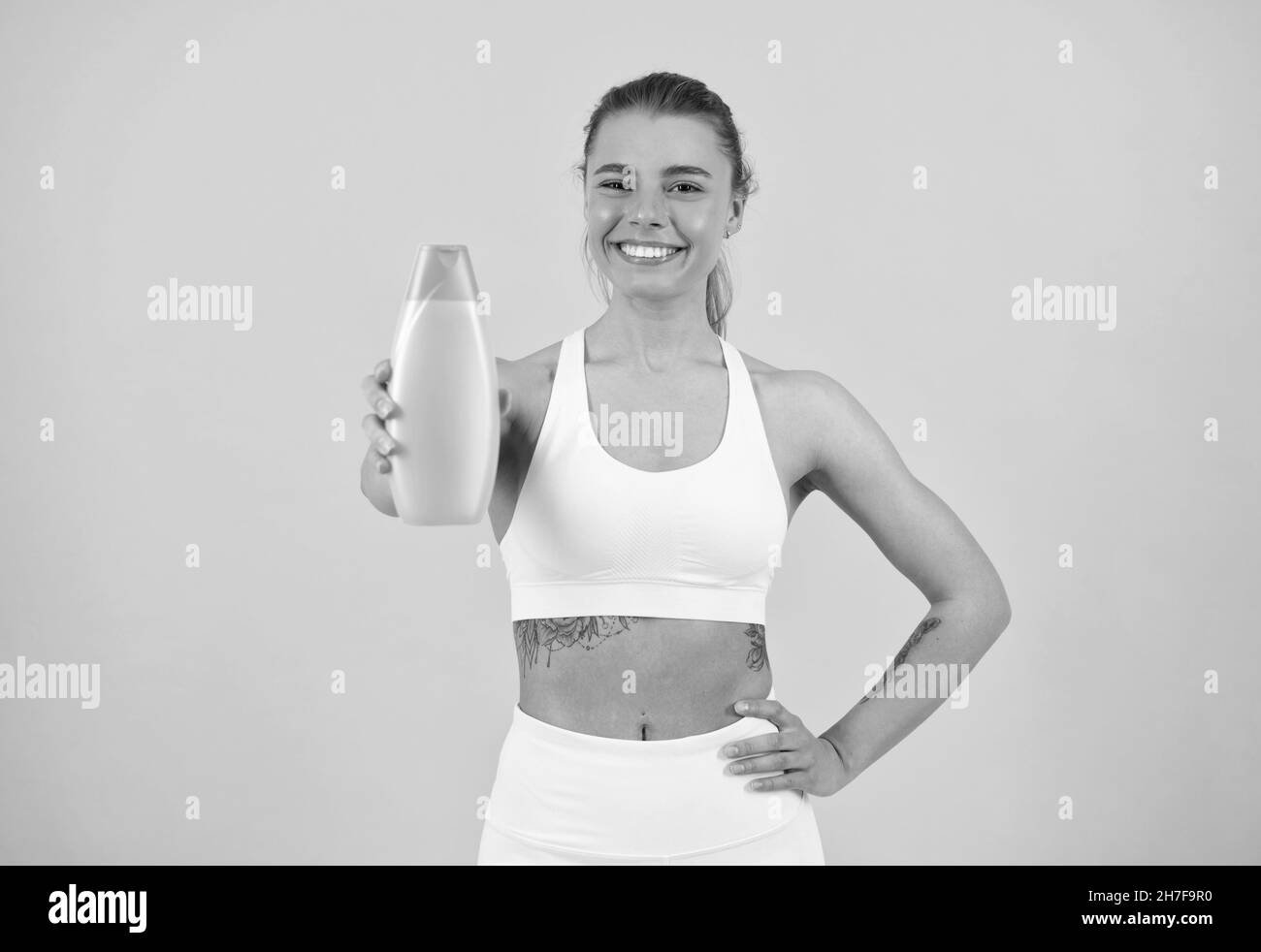 happy girl showing bottle of hair shampoo conditioner or body lotion