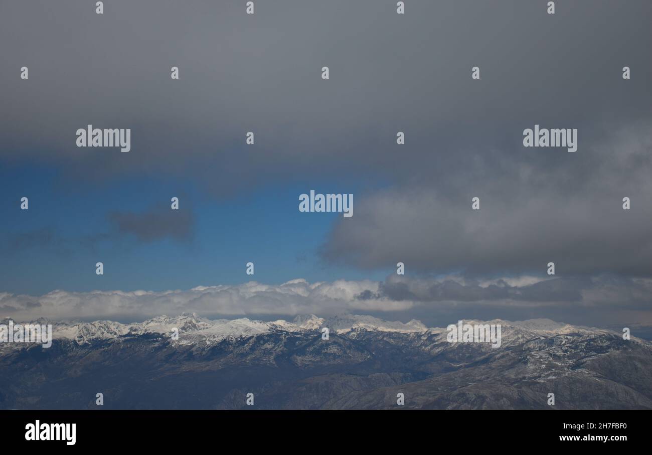 View of snowy mountain peaks under a cloudy sky Stock Photo - Alamy