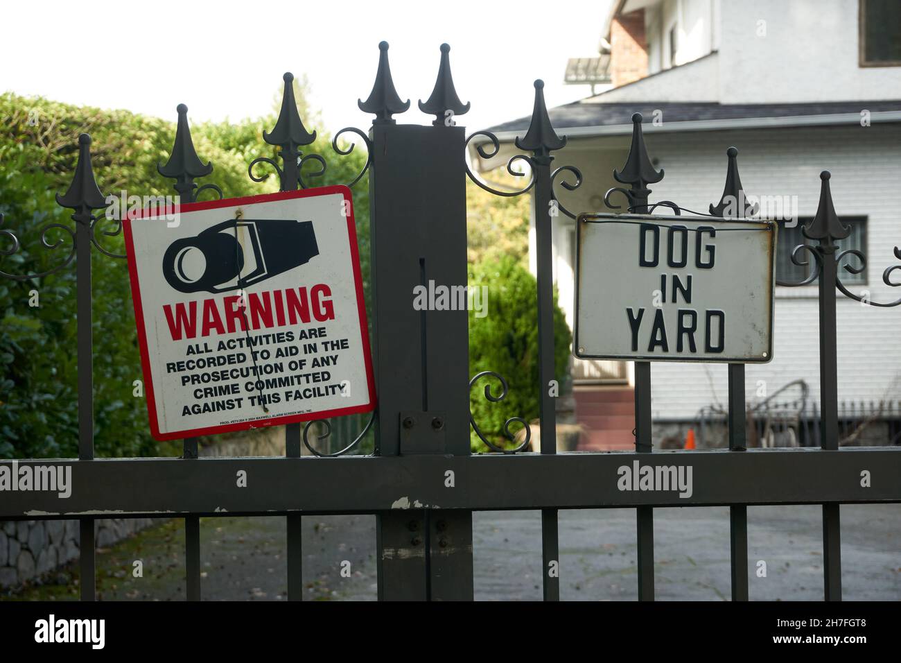 Video surveillance sign and beware of dog warning signs on the metal gate of a house in Vancouver, British Columbia, Canada Stock Photo