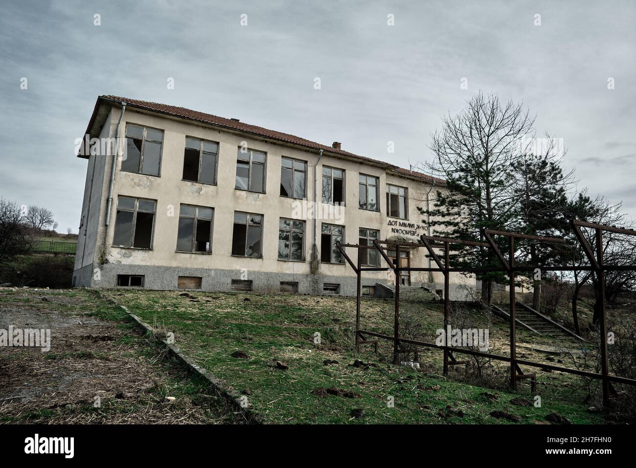 Bulgaria, Kardzali. Old brownfield and abandoned soviet type school with overcast and very cloudy sky. Stock Photo