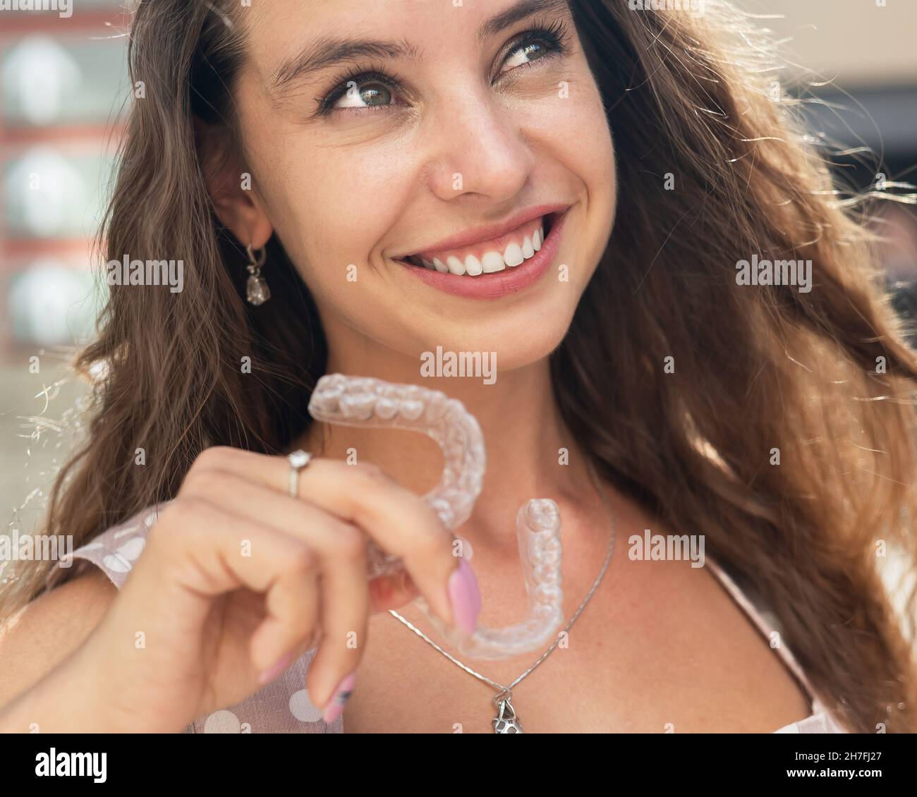 Beautiful caucasian woman holding transparent mouth guards for bite