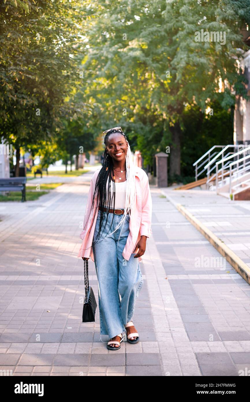 Beautiful young black woman walking at street Stock Photo - Alamy