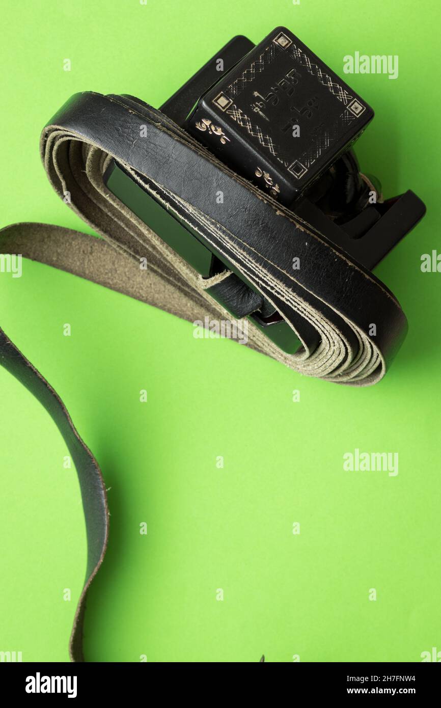 Top view of black strips of tefillin on a green background, (To the editor - the plastic is written in Hebrew - tefillin) Stock Photo