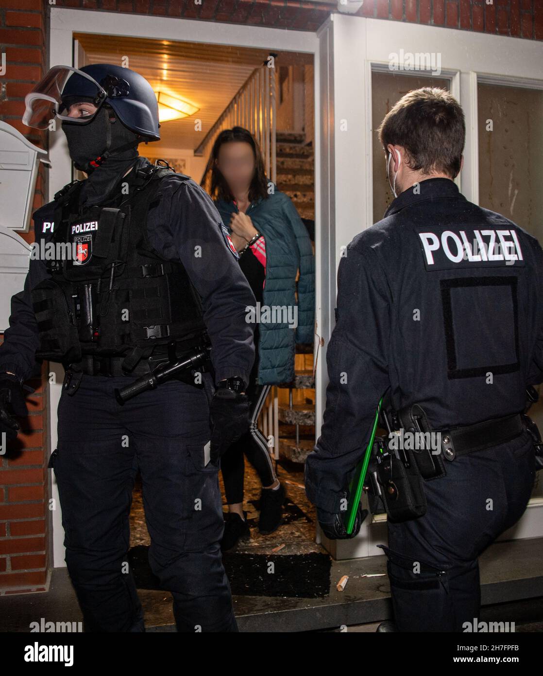 23 November 2021, North Rhine-Westphalia, Gütersloh: A suspect is led away from a house by police officers. Police have arrested several suspects in simultaneous raids in several countries against so-called 'tarpaulin slashers'. It is said to be about gangs of thieves who steal loads from trucks. Photo: Lino Mirgeler/dpa - ATTENTION: The person was pixelated for legal reasons Stock Photo