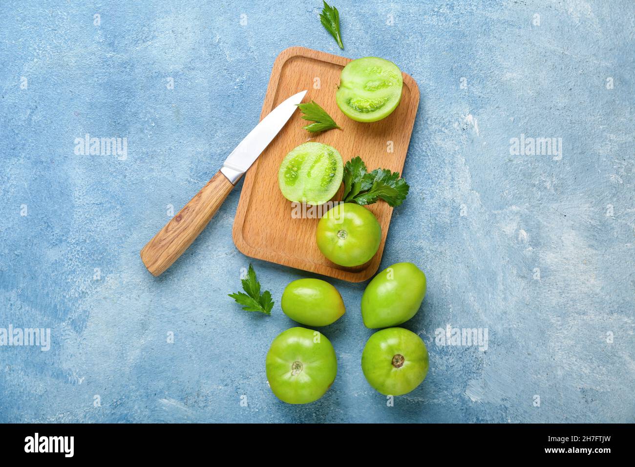 Wooden board with green tomatoes and knife on color background Stock ...
