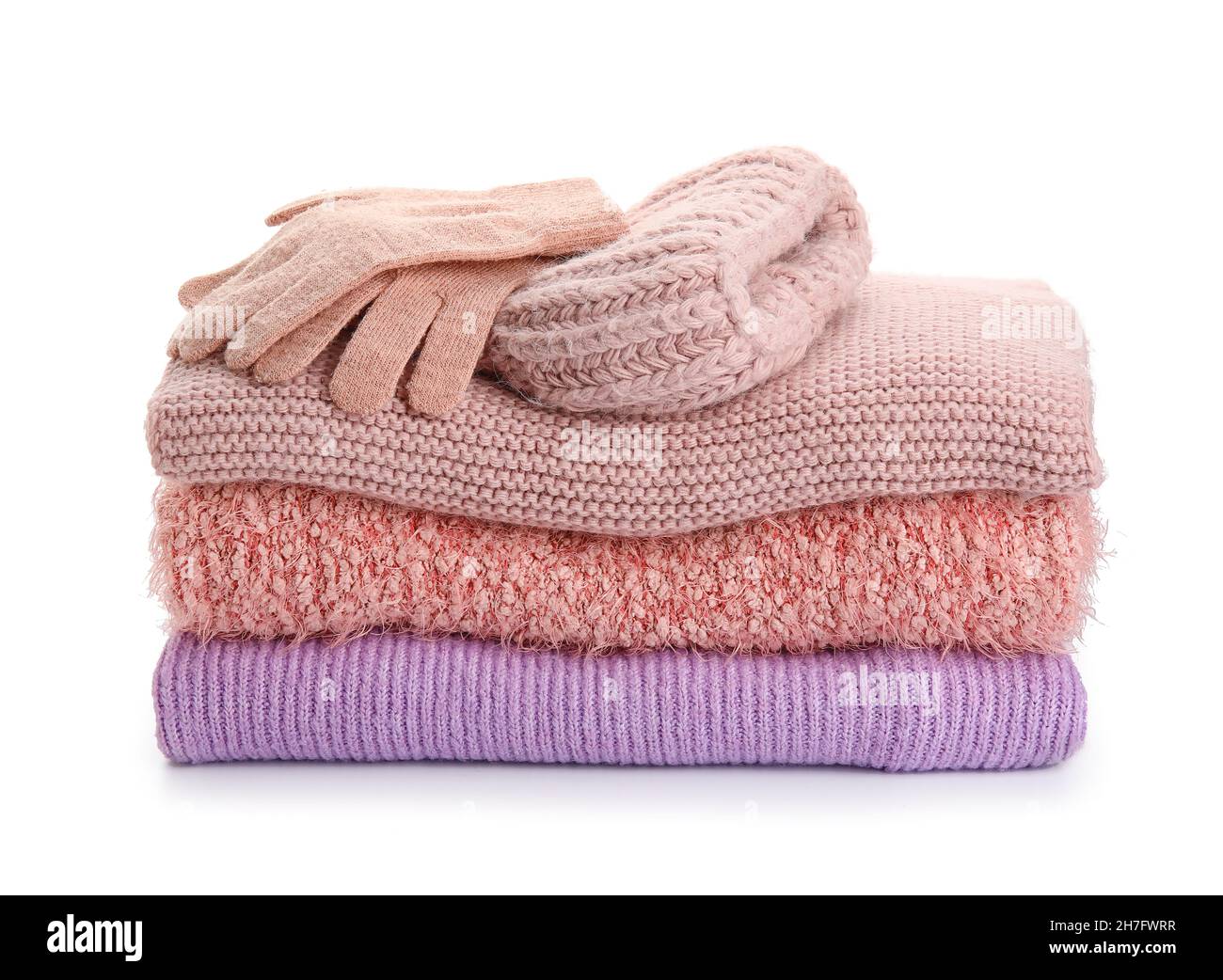 Stack of stylish sweaters, gloves and hat on white background Stock Photo