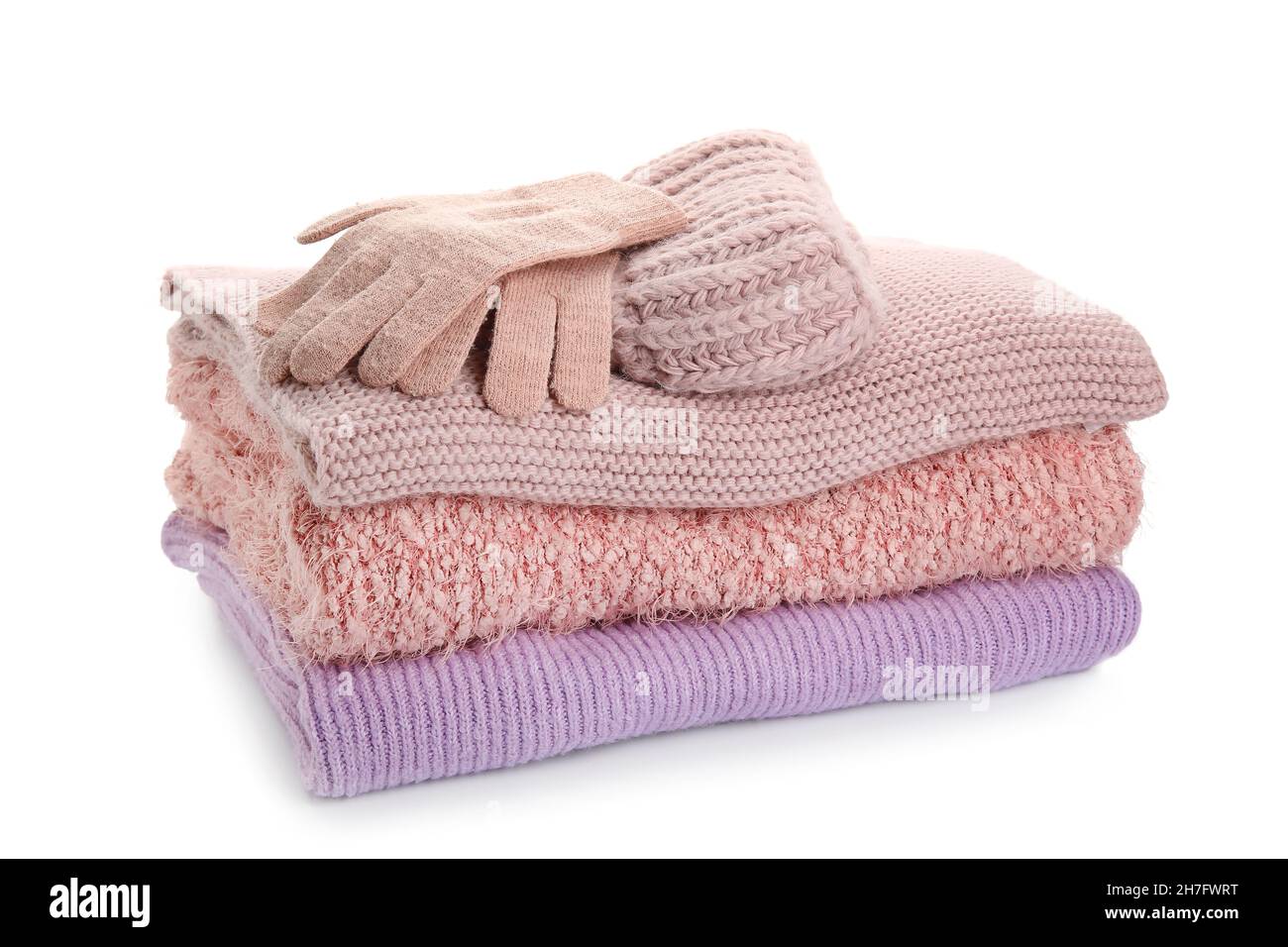 Stack of stylish sweaters, gloves and hat on white background Stock Photo