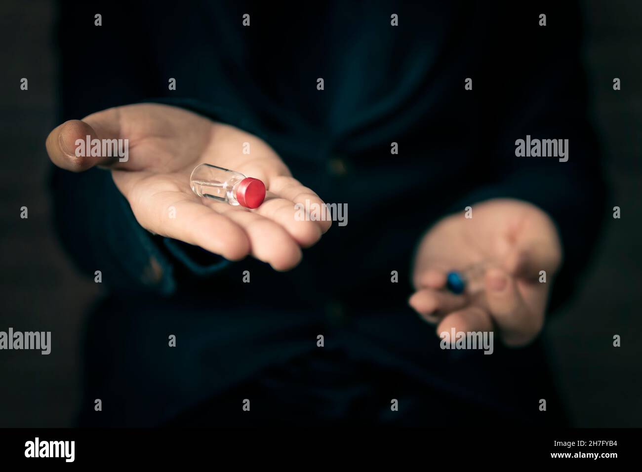 Medical concept. The choice of medication by analogy with the matrix. Choosing the best vaccine. Man holds a blue and red ampoule in his hands. the se Stock Photo