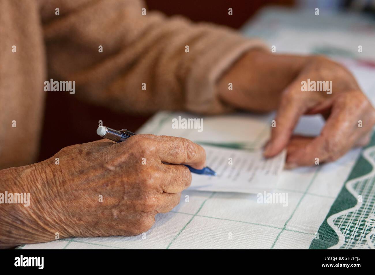 A close up of the hands of an elderly woman's hands writing a note MR - Model Released Stock Photo