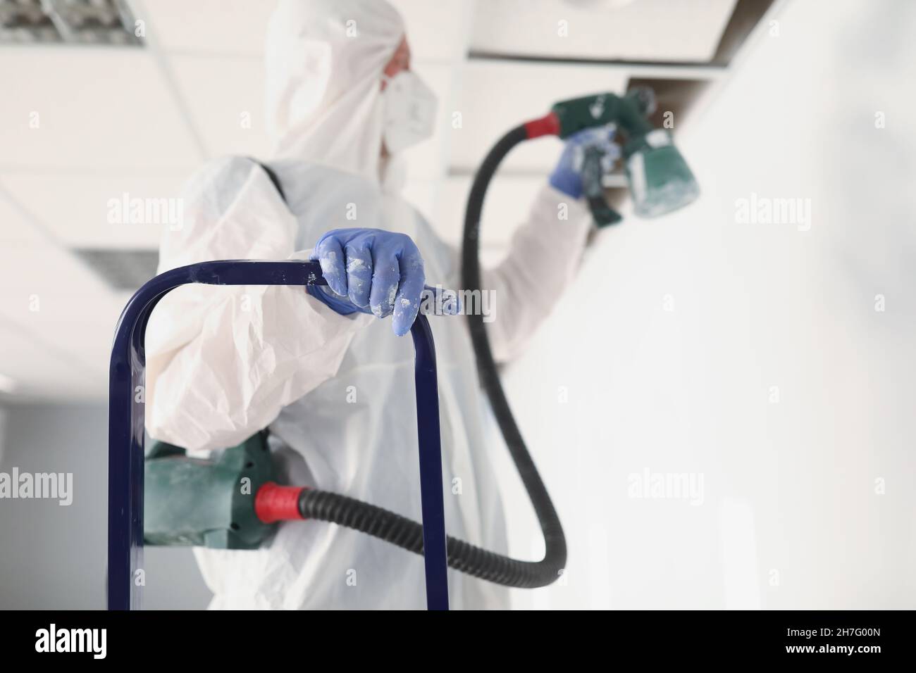 Renovation worker paint wall in uniform using spray gun Stock Photo