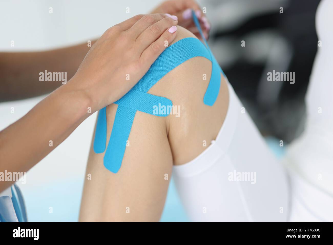 Physiotherapist apply kinesiology tape to patient knee in clinic Stock