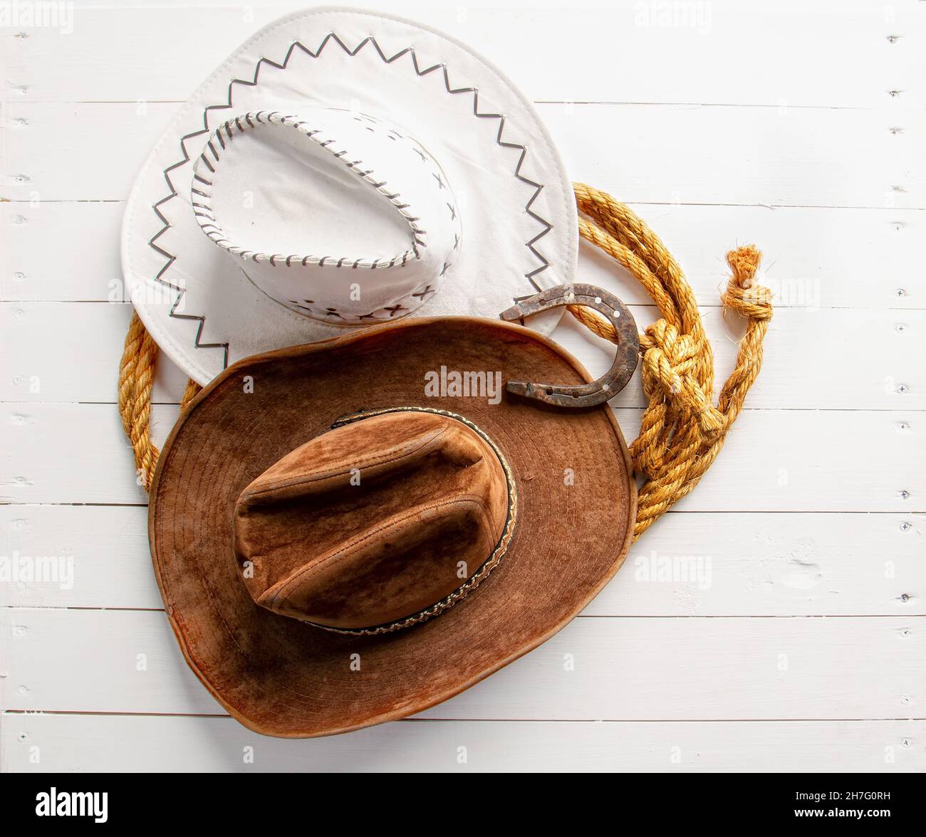 Classic brown and white cowboy hat lasso and horseshoe wild west still life on rough white wooden table Stock Photo