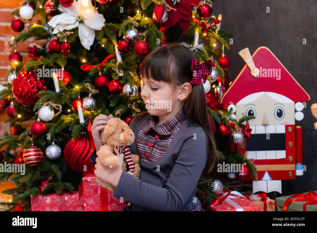 little white girl in near the Christmas tree with a Teddy bear ...