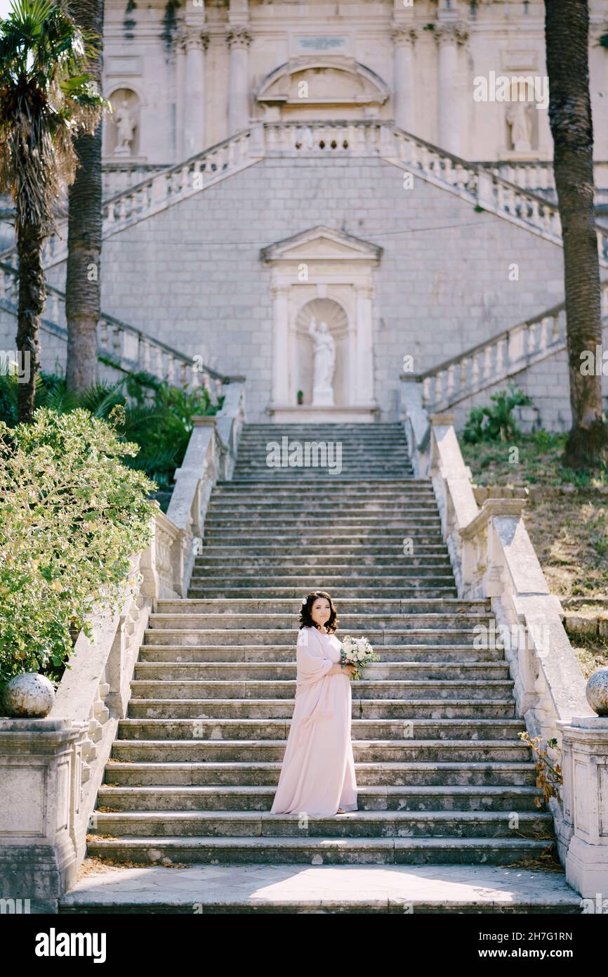 Bride with a bouquet stands on the steps of a luxury villa Stock Photo ...