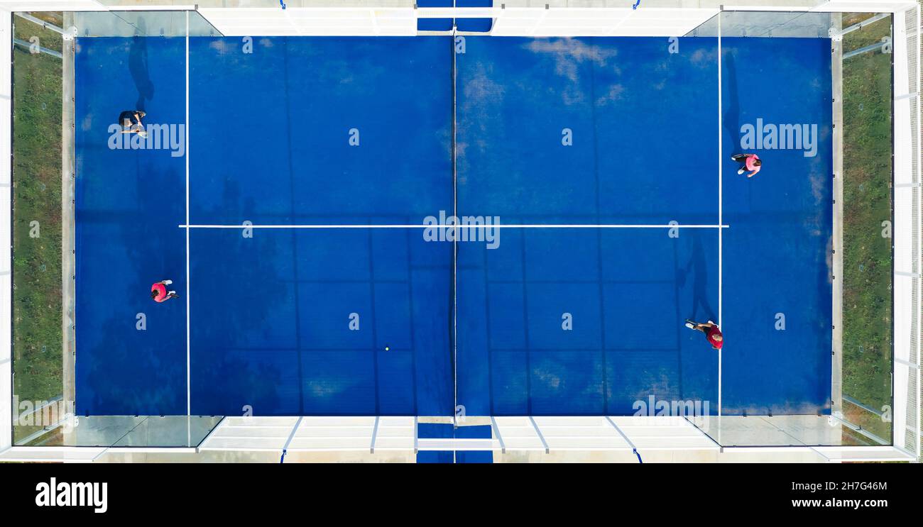 View from above, stunning aerial view of some people playing on a blue padel court. Padel is a mix between Tennis and Squash. It's usually played in d Stock Photo