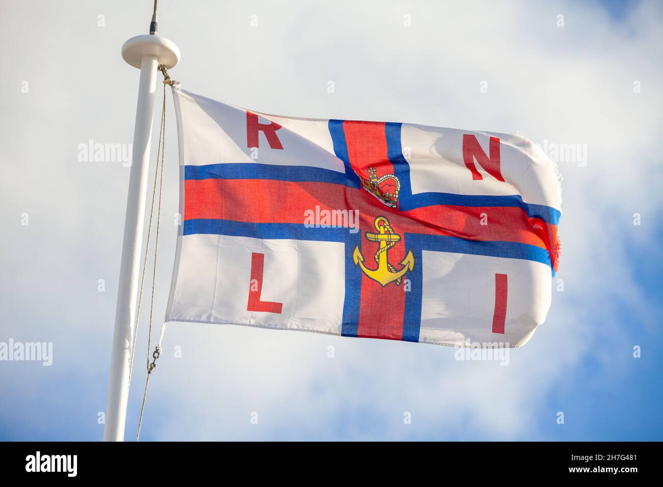 A flag of the Royal National Lifeboat Institution RNLI flying in the wind Stock Photo