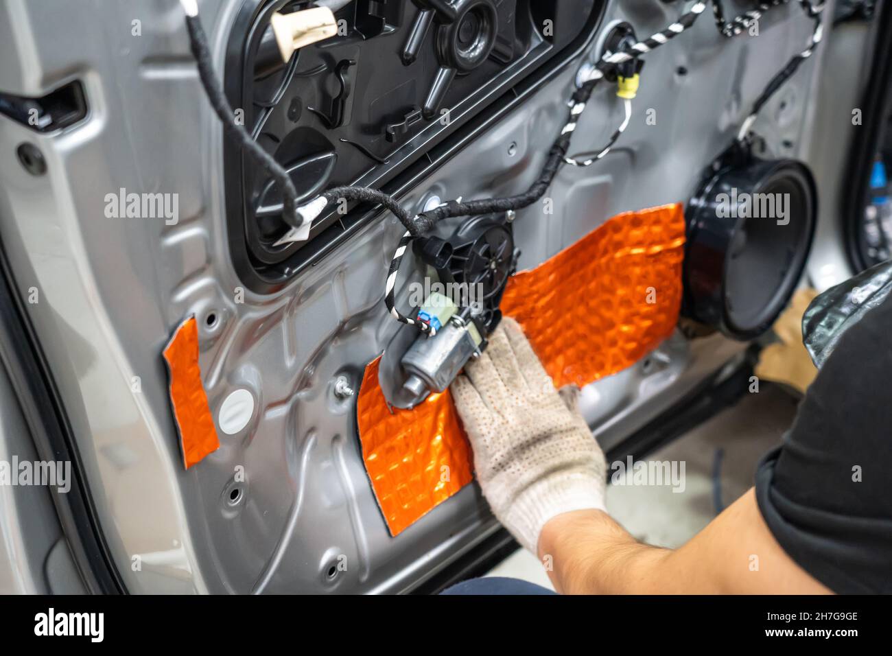 Worker installing special acoustic and vibrationdamping material for noise insulation on car