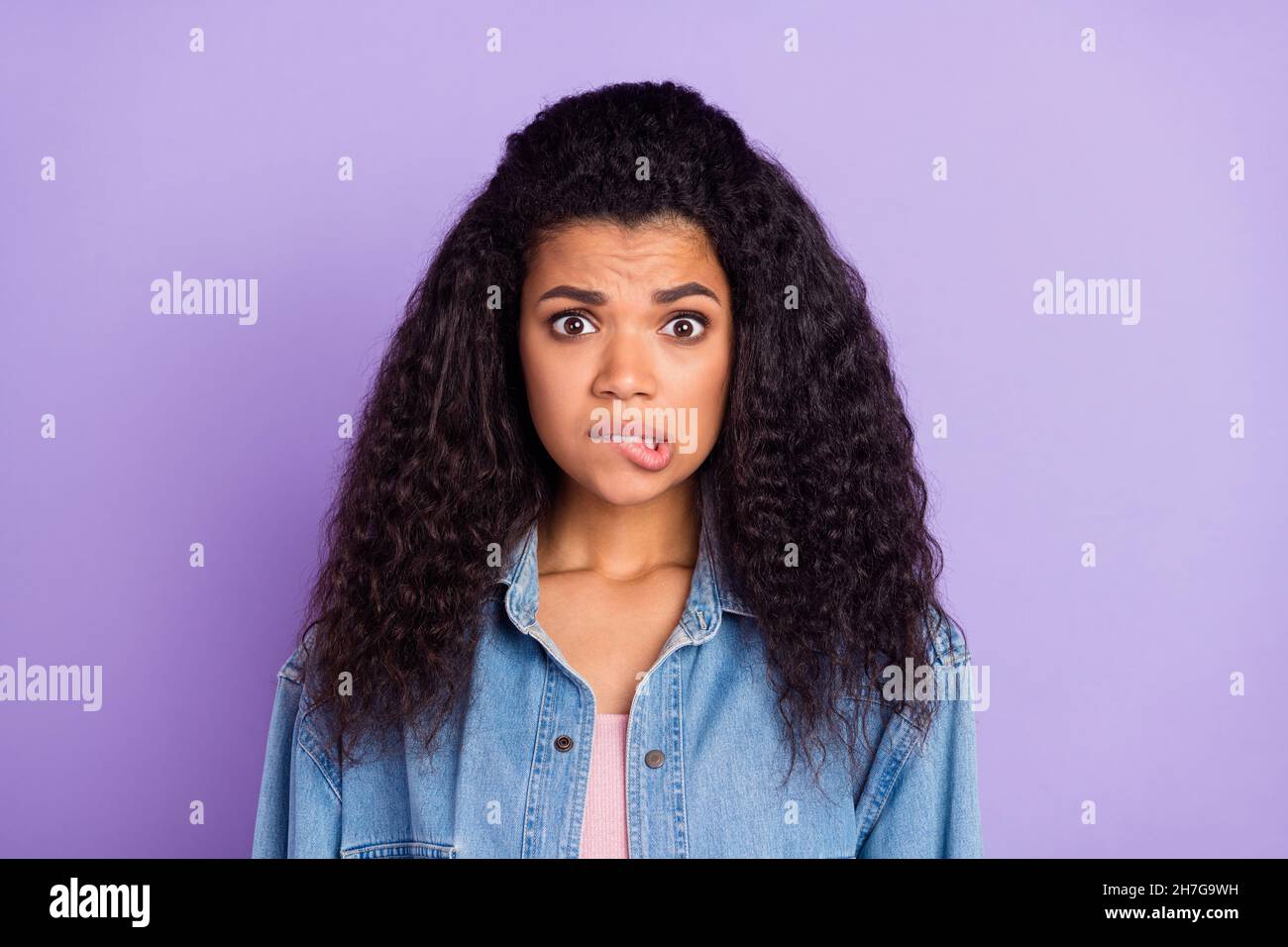 Photo of sweet guilty dark skin lady wear denim shirt biting lip isolated purple color background Stock Photo