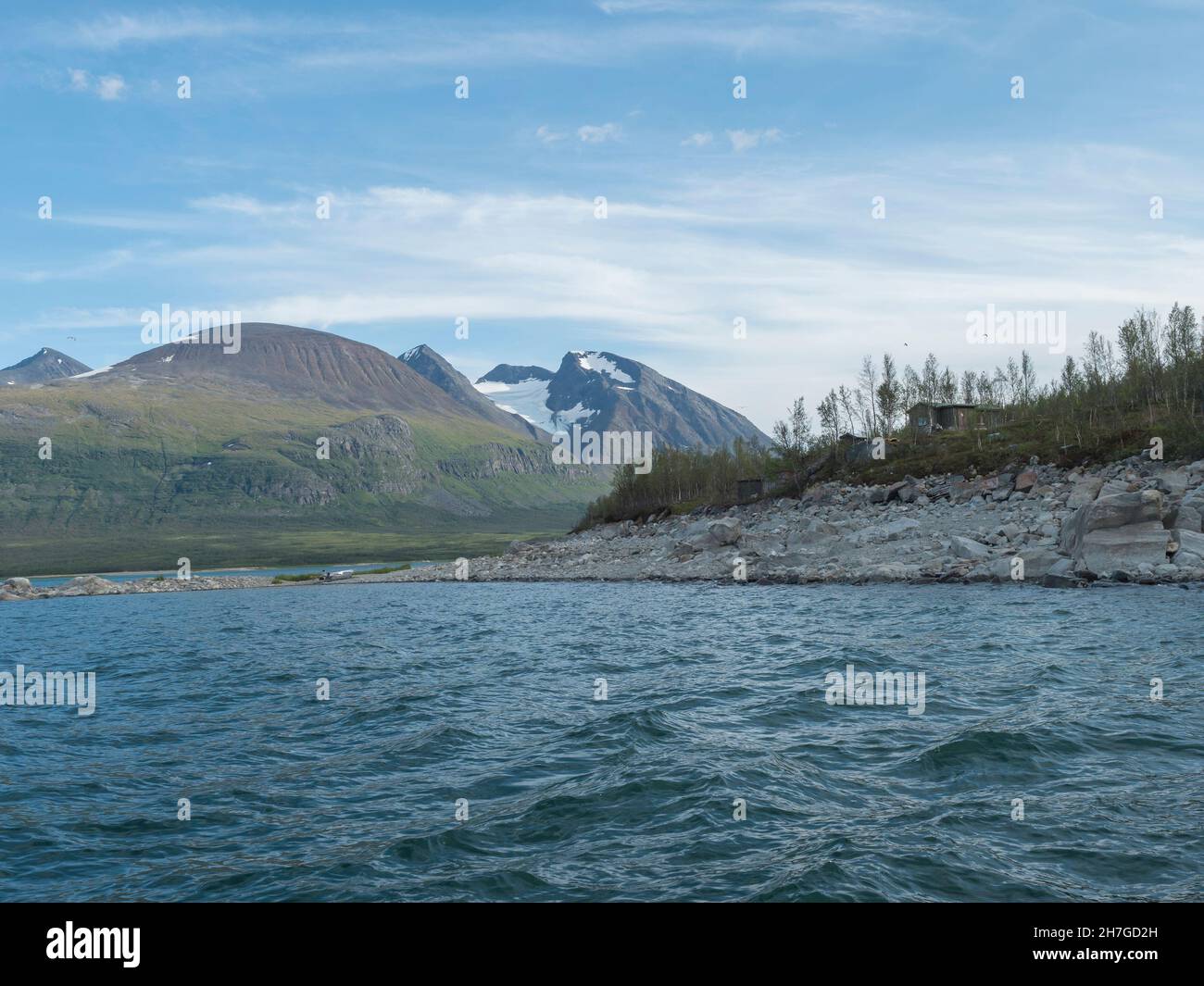 Summer view of over lake Akkajaure to Akka, Ahkka mountain massif with snow and glacier and Anonjalmme saami setllement. Start point of Stock Photo