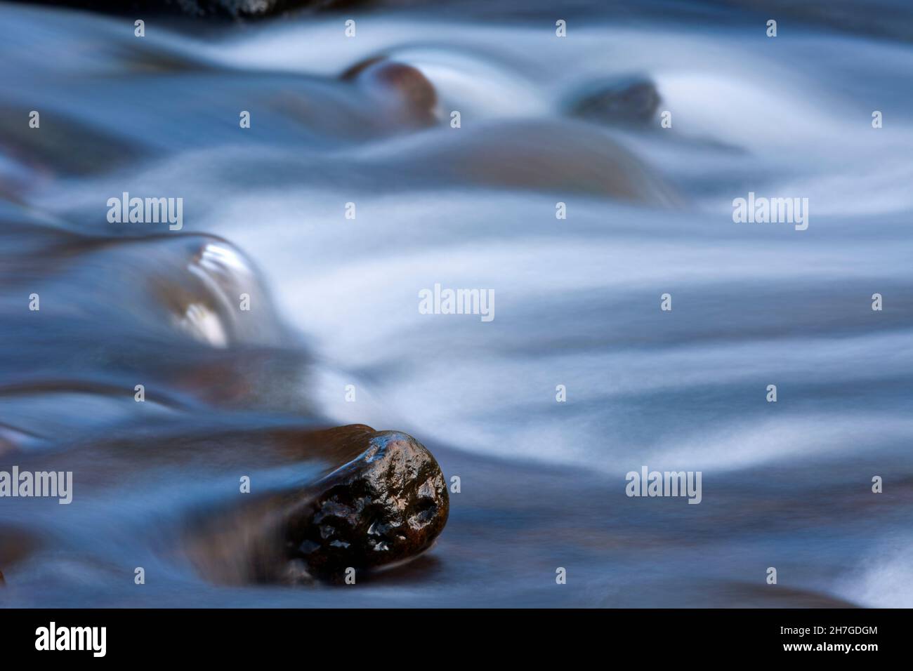 water flowing over stones in hill stream, showing silky texture through long exposure time, Lower Saxony, Germany Stock Photo