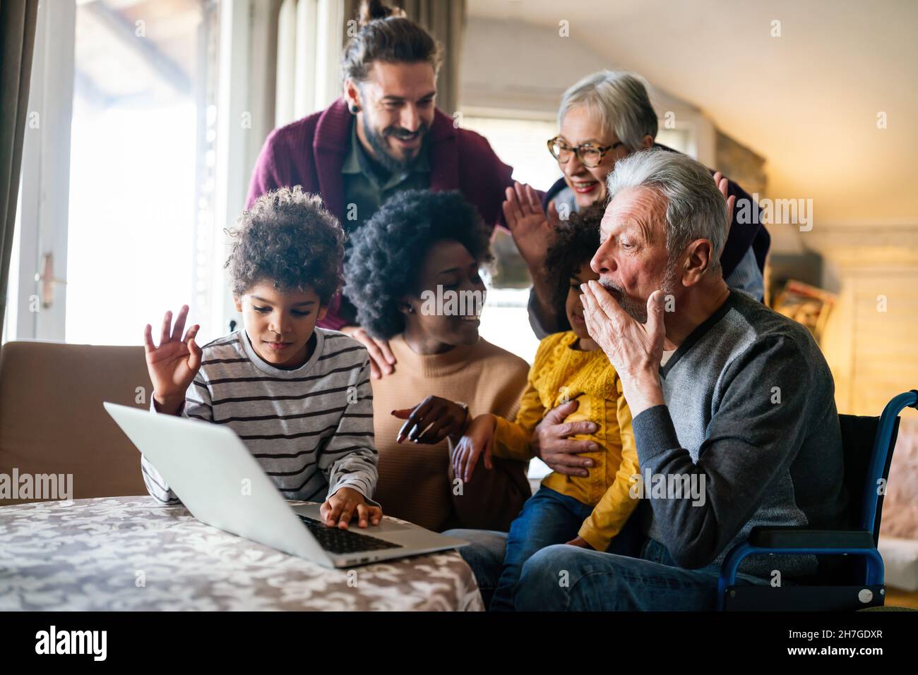 Happy multi-generation family gathering around notebbok and having fun during a video call Stock Photo