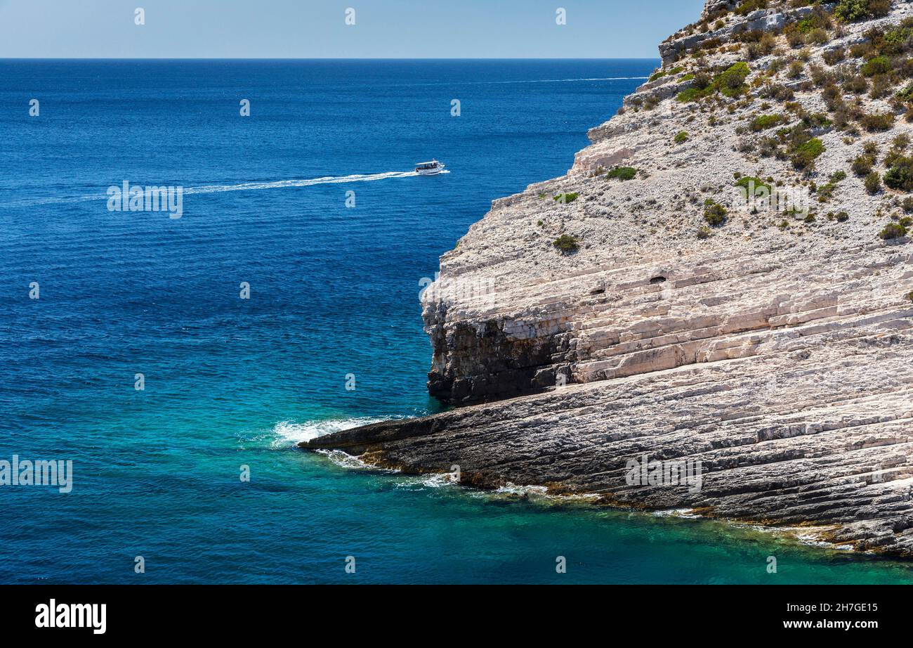 Boat sailing behind the rock in island Vis Stock Photo