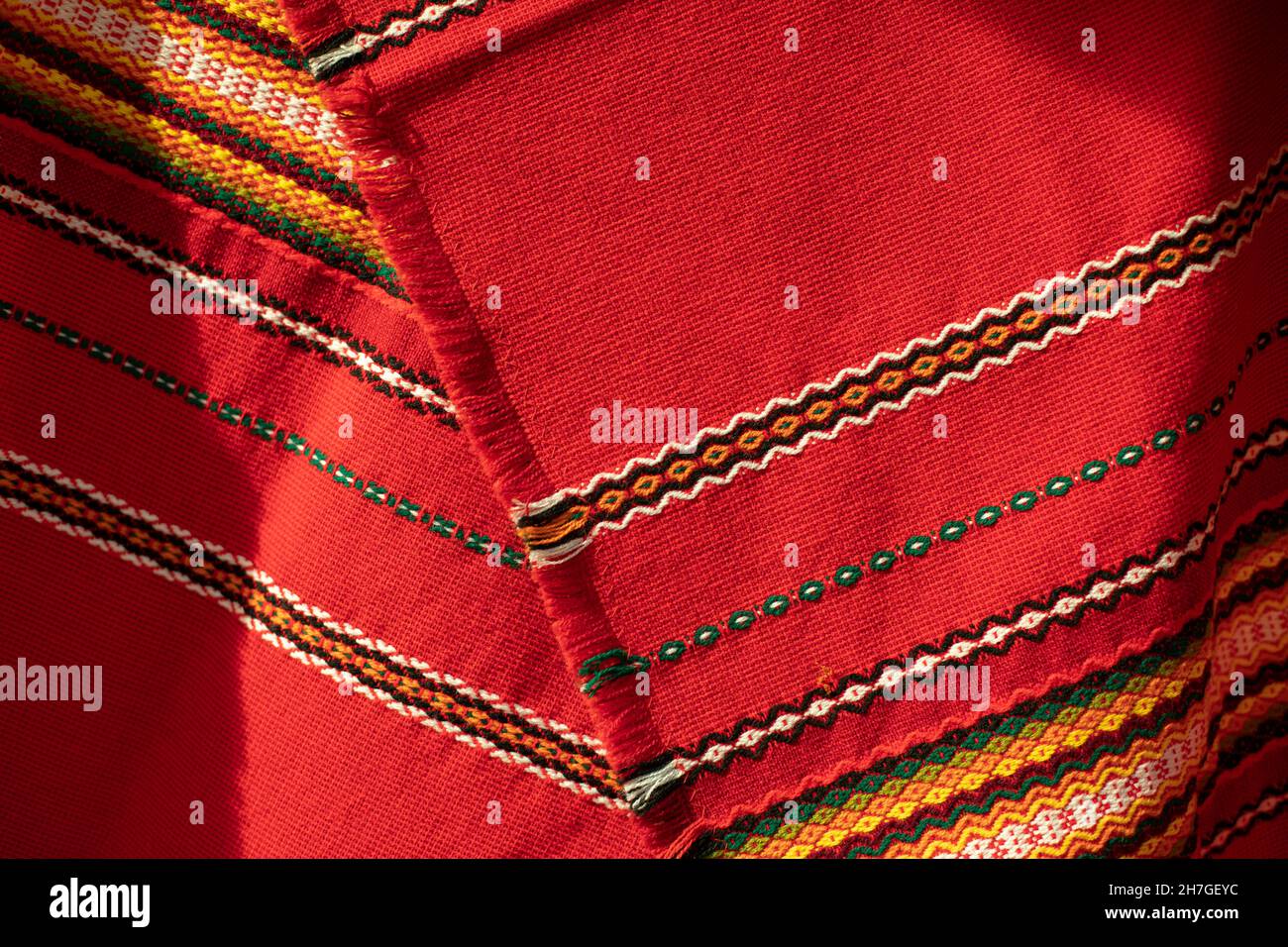 Red tablecloth in Russia. Folk pattern on the fabric. Fabric material in the Slavic peoples. National patterns from rustic weaving. Stock Photo