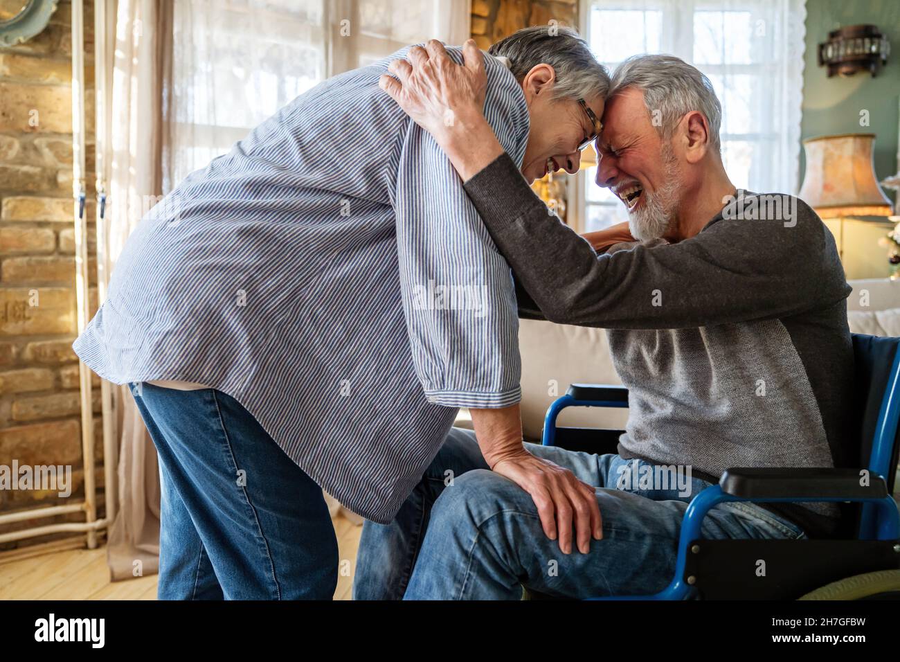 Mature man with disability in wheelchair spending time together with his wife at home Stock Photo