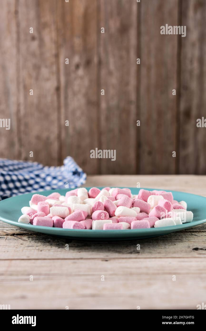 Sweet marshmallows topping in a blue plate on wooden table Stock Photo
