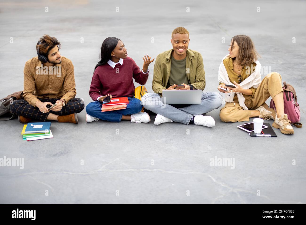 Students sitting and using smartphones on asphalt Stock Photo