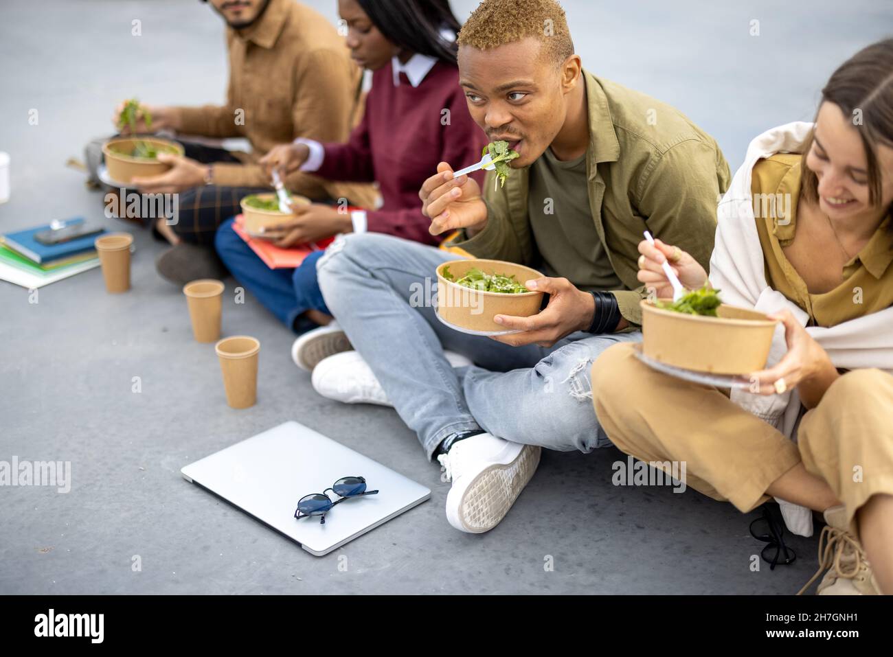 Students eating salad during lunch on asphalt Stock Photo