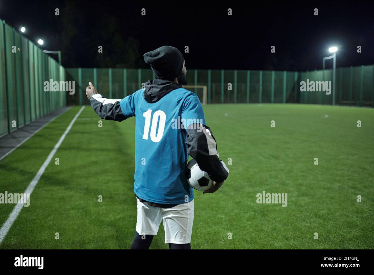 Back view of young professional football trainer with soccer ball
