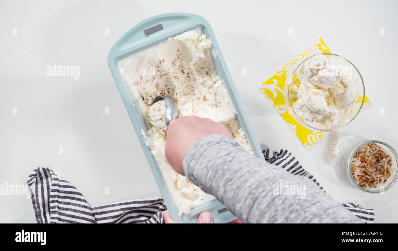 Flat lay. Scooping homemade coconut ice cream into a glass ice cream bowl Stock Photo Alamy