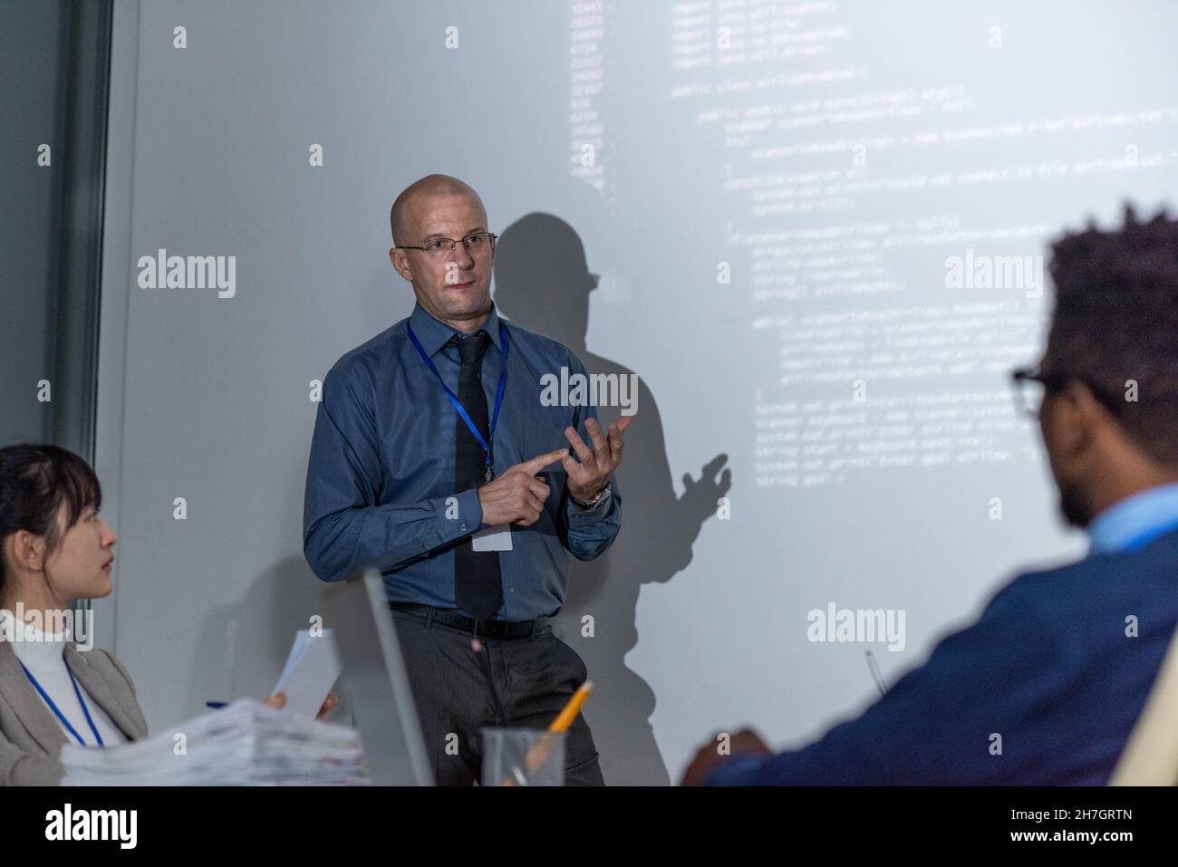 Experienced it-developer in formalwear explaining new way of decoding data to audience during presentation Stock Photo