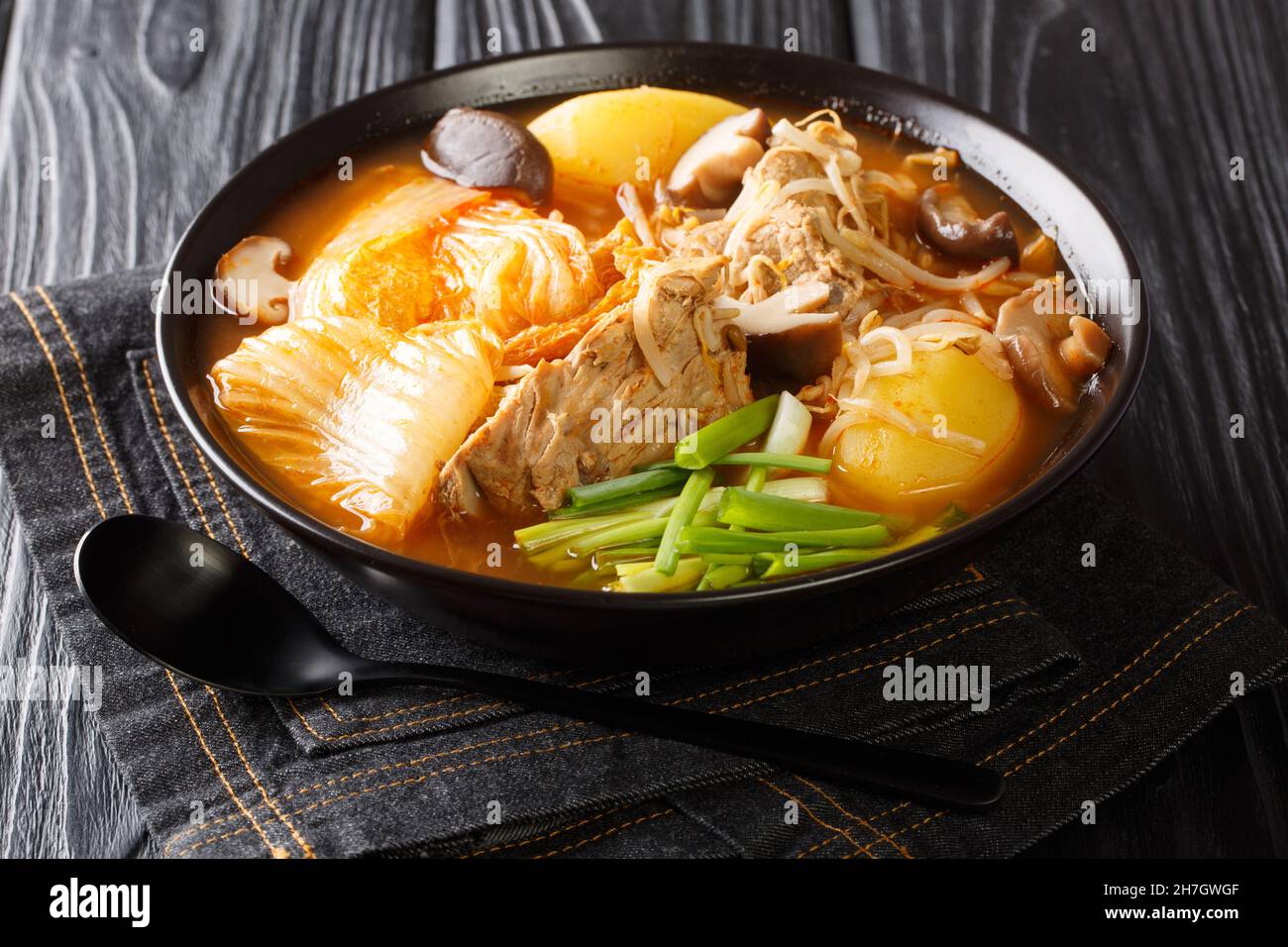 Tasty spicy Gamjatang Korean Pork Bone Soup with creamy potatoes and tender juicy pork bone meat close up in the bowl on the table. Horizontal Stock Photo