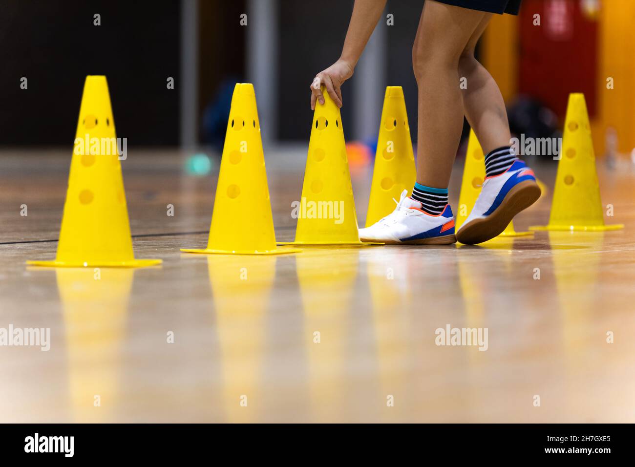 Row of Yellow Training Cones at Indoor Practice Field. Young Player on Training With Practice Trail. Physical Education Class For Youths Stock Photo