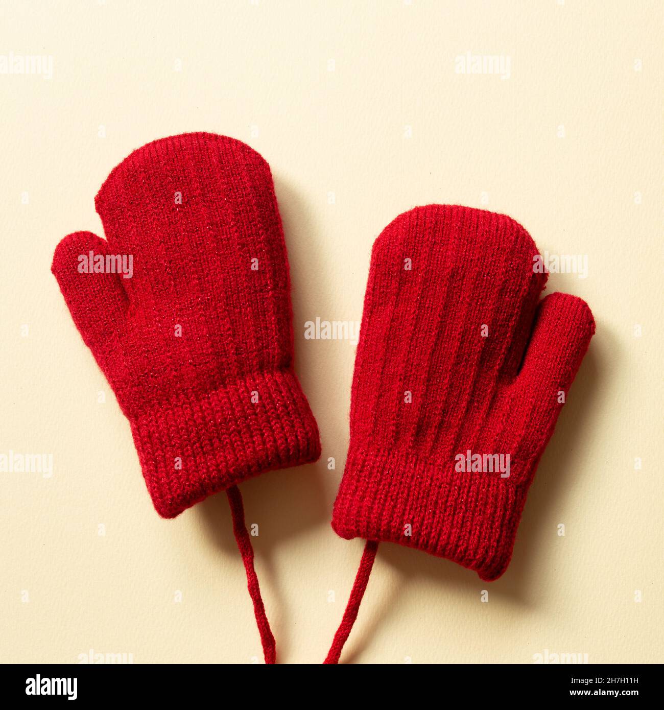 Winter red knitted gloves on beige background. top view, copy space Stock Photo