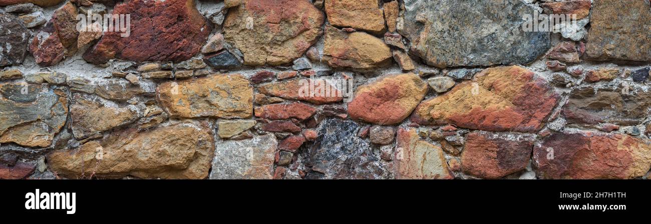 Old stone wall surface in abandoned building. Rough multicolored natural stone, texture panorama Stock Photo