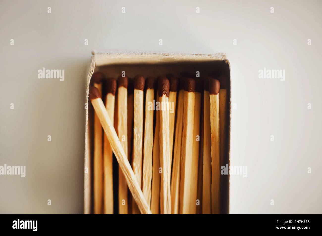 In an open cardboard matchbox lying on a white table, there are wooden matches illuminated by light. Flammable objects. Household items. Stock Photo