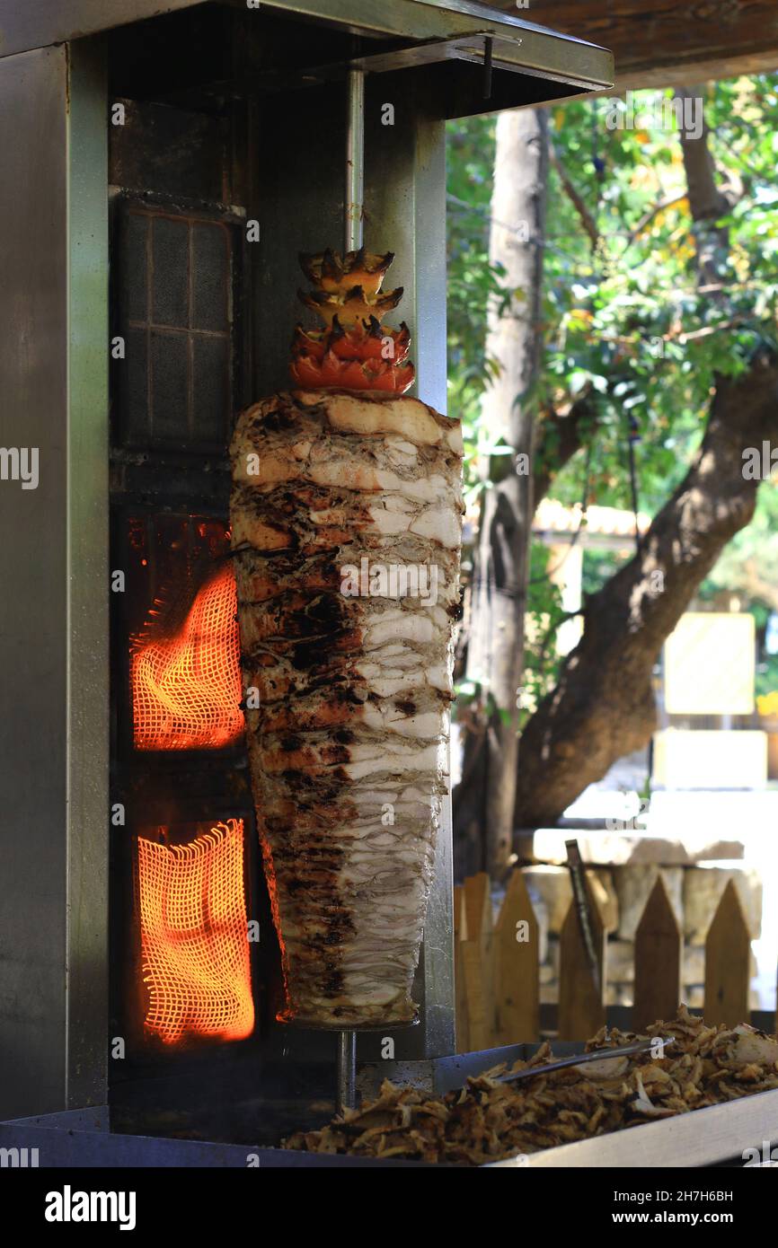 A chicken shawarma skewer roasting on a rotating pole. Stock Photo
