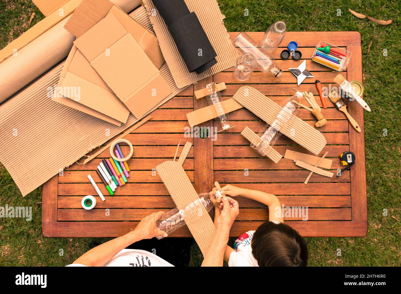 grandfather and grandson building airplanes with recycled material (cardboard, PVC bottles, wood). work ideas circular economy, recycling, environment Stock Photo